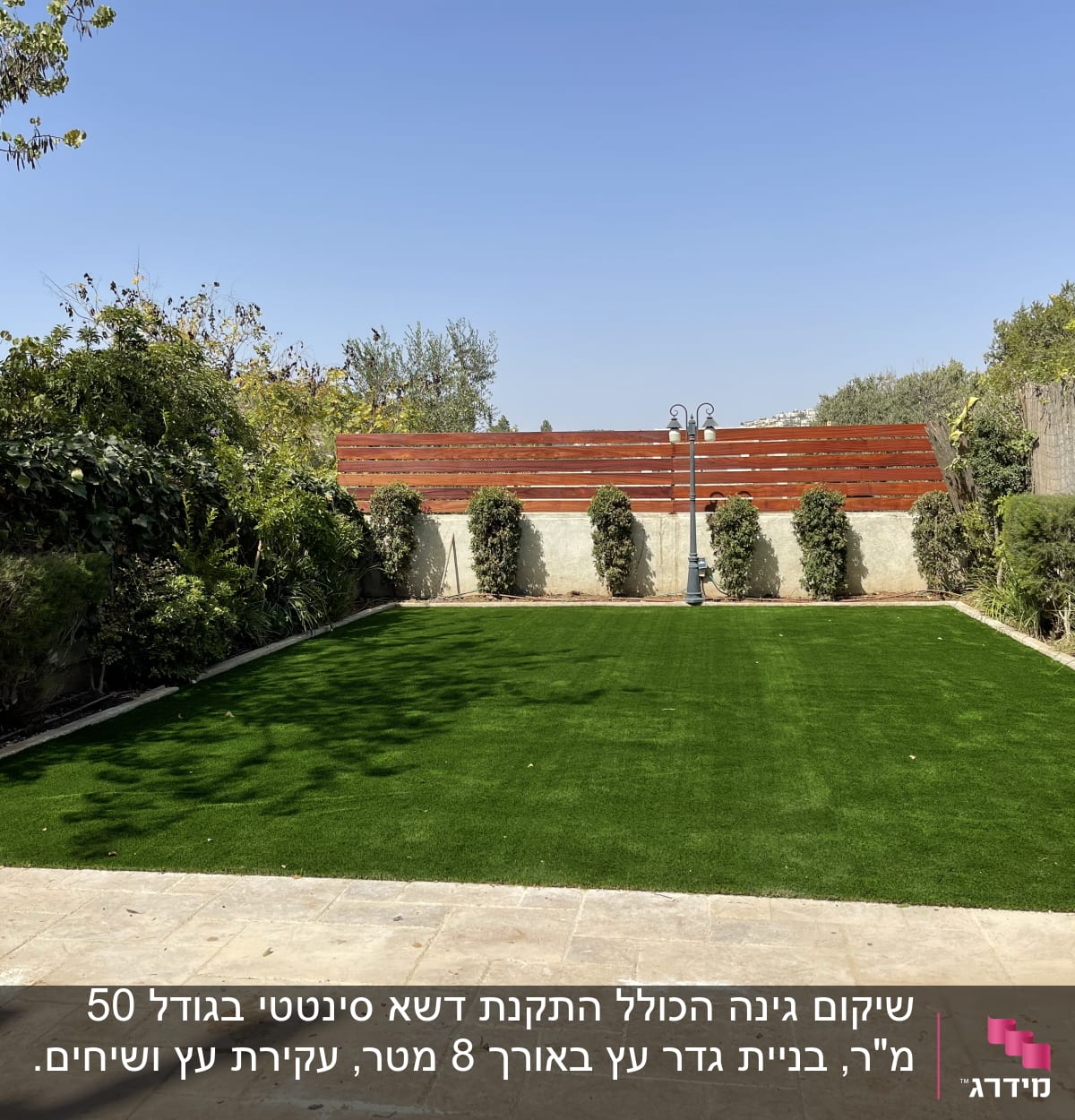 דשא ירוק מוקף בצמחייה וגדר עץ